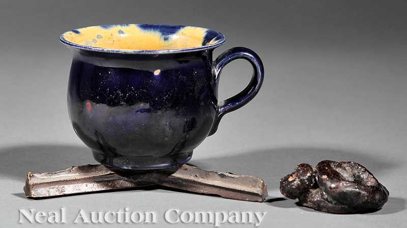 George Ohr Humorous Tea Cup: A George Ohr Humorous Tea Cup, stamped "G.E. OHR/Biloxi, Miss.", in the form of a chamber pot and contents with stilt, height 2 3/8 in., (3 pcs.)