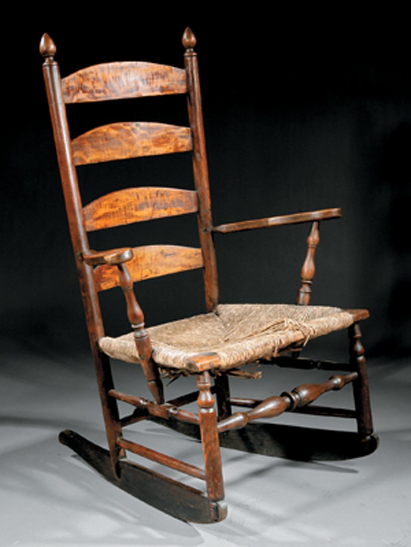 An Early American Mixed Woods Ladderback Rocking: An Early American Mixed Woods Ladderback Rocking Chair, late 18th/early 19th c., having four arched slats, finials, scrolled splayed arms, turned uprights, rush seat, turned legs, bulbous stretcher, k