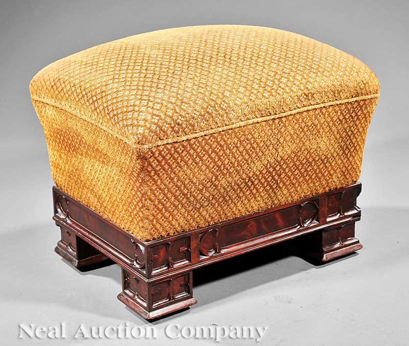 American Gothic Carved Mahogany Footstool: A Large American Gothic Carved Mahogany Footstool, c. 1850, everted upholstered cushion, base with trefoil feet, casters, height 19 in., width 24 in., depth 18 in