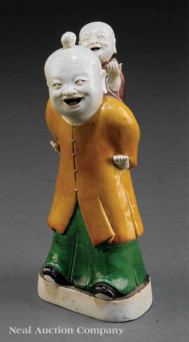 ChineseBiscuit-Glazed Porcelain Group: A Chinese Famille Verte Biscuit-Glazed Porcelain "Piggyback" Group, 18th c., modeled as a large smiling boy carrying a smaller smiling boy on his back, probably a rendition of the He-He Erxian twin Im