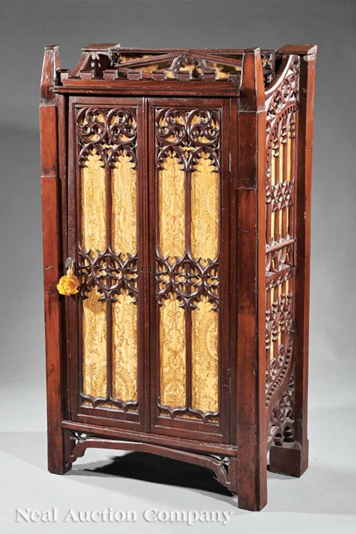 American Gothic Carved Mahogany Side Cabinet: An American Gothic Carved Mahogany Side Cabinet, c. 1850, crenellated cornice, tracery door and sides inset with gold brocade, squared feet joined by spandrels, height 57 in., width 33 in., depth 16 i