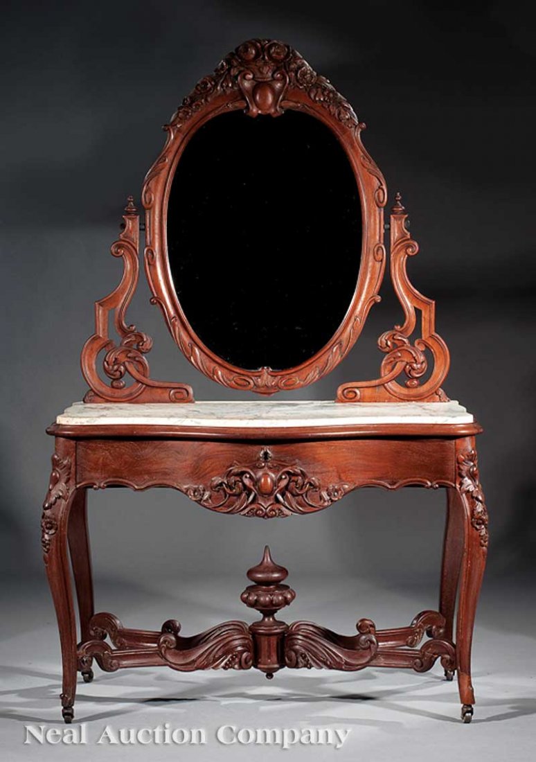 Carved Mahogany "Duchesse" Dressing Table: A Fine American Rococo Carved Mahogany "Duchesse" Dressing Table, mid-19th c., oval mirror with scrolled surround, surmounted by flower basket over a cabochon, scroll supports, serpentine variegated w