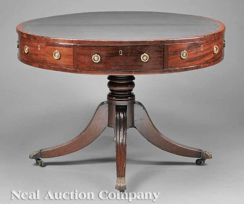 George III Carved Mahogany Rent Table: A George III Carved Mahogany Rent Table, c. 1800, revolving top with inset leather, alternating frieze drawers; turned support, four reeded downswept legs, brass paw feet, casters, height 29 1/2 in., 
