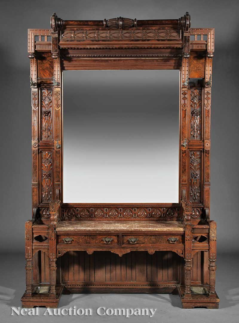 Carved and Burled Walnut Hall Stand: An American Aesthetic Carved and Burled Walnut Hall Stand, mid-19th c., turned crest, lattice frieze, beveled mirror flanked by floral panels fitted with brass griffin hooks, umbrella stands flanking 