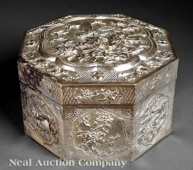 A Chinese Silver `Heavenly Creatures' Box: A Chinese Silver `Heavenly Creatures' Octagonal Box, 19th c., faceted sides repoussé decorated with shaped cartouches enclosing a dragon, a phoenix, a qilin, and a tortoise, between insect and flower