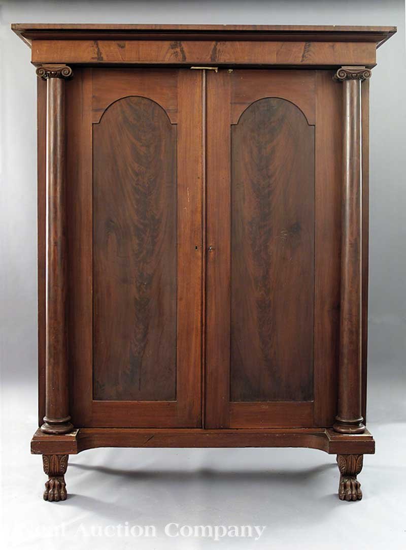 An American Mahogany Gentleman's Wardrobe: An American Classical Carved Mahogany Gentleman's Wardrobe, early 19th c., Philadelphia, stepped molded cornice above a figured frieze, Ionic columns flanking arched doors, fitted interior of shelves 