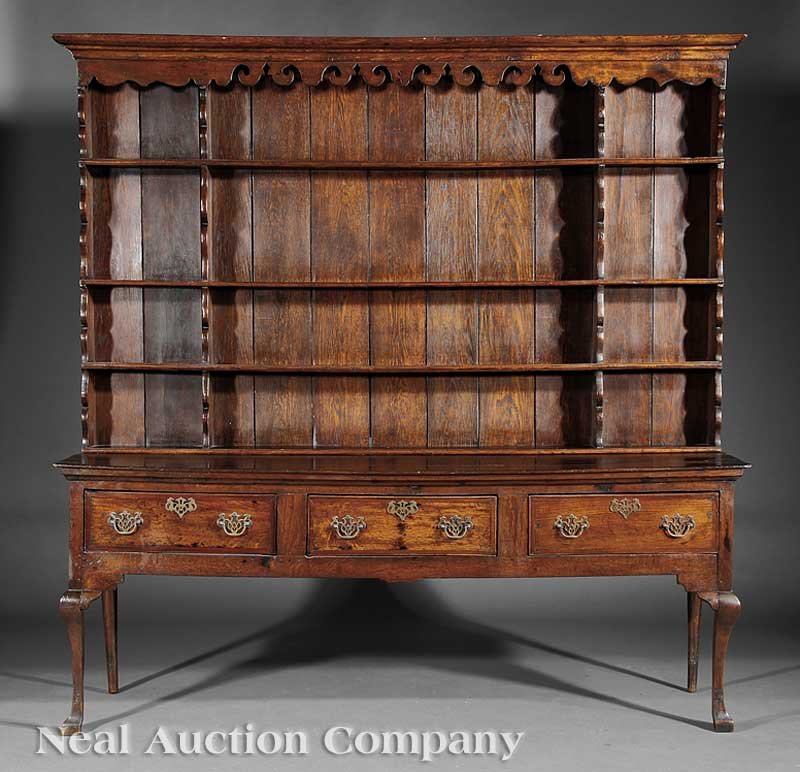 A Queen Anne Carved Oak Welsh Dresser: A Queen Anne Carved Oak Welsh Dresser, 18th c. and later, superstructure with molded cornice, scalloped frieze, and four shelves, the base with three drawers, cabriole legs, blocked feet, height 82 in