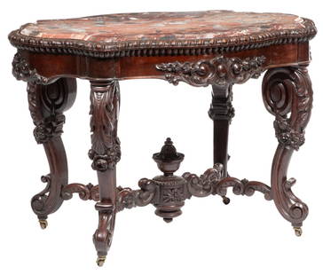American Rococo Carved Mahogany Turtle Top Center Table h. 31 in., l. 44 1/2 in., w. 31 in.: American Rococo Carved Mahogany Turtle Top Center Table, 19th c., probably Alexander Roux, New York, inset molded marble, gadrooned edge, scrolled and acanthus legs, C scrolled stretcher surmounted by