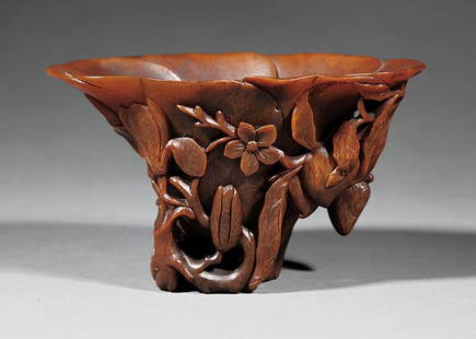 Chinese Carved Rhinoceros Horn Libation Cup: A Fine and Large Chinese Carved Rhinoceros Horn Libation Cup, 18th c., carved as a large open flower borne on openwork branches issuing lychee and peach fruit and magnolia and prunus blossoms, height