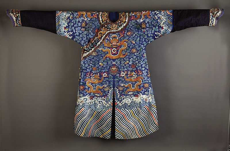 Chinese Embroidered Blue Silk Nine Dragon Robe: A Chinese Embroidered Blue Silk Nine Dragon Robe, Jifu, Qing Dynasty (1644-1911), worked in satin and knot stitch and couched metallic threads with dragons in flight amid Buddhist emblems above a terr