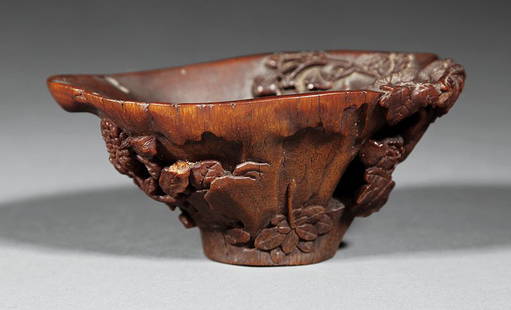 Chinese Carved Rhinoceros Horn Libation Cup: A Chinese Carved Rhinoceros Horn Libation Cup, 17th/18th c., carved as a partly rotten tree stump with new-growth chrysanthemum, peony and grasses relief carved along the sides, height 2 1/4 in., widt