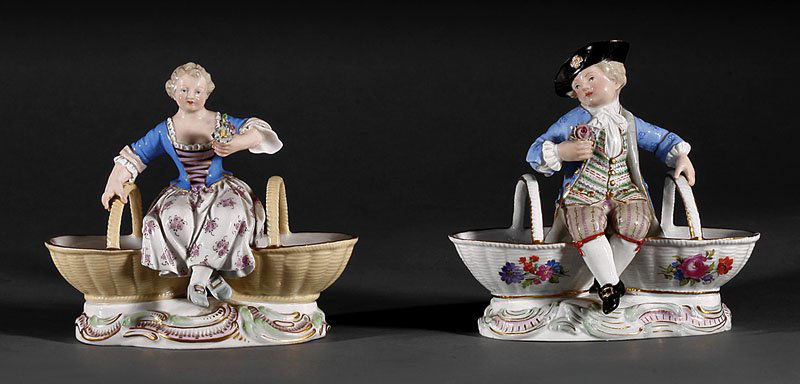 Meissen Porcelain Figural Bonbon Dishes: A Pair of Meissen Porcelain Figural Bonbon Dishes, late 19th/early 20th c., each seated on baskets, blue crossed swords marks, height 5 1/4 in., width 5 1/2 in., depth 3 1/2 in