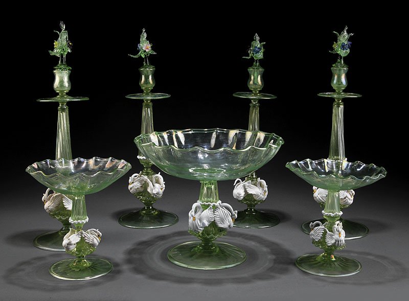 Venetian Glass Table Garniture: An Antique Venetian Glass Table Garniture, 19th c., comprising a compote, two tazzas, and 4 candlesticks, 3 applied swans on each stem, removable floral finials, compote height 9 in., diameter 11 in.;