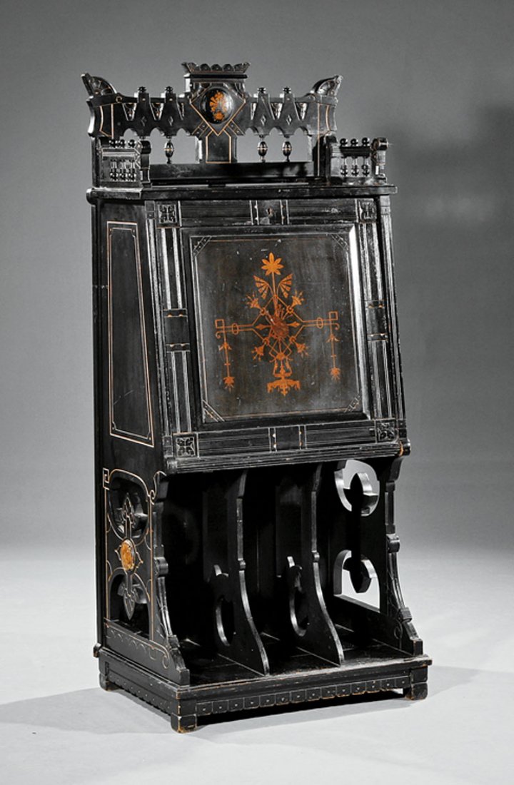 An American Aesthetic Music Cabinet: An American Aesthetic Ebonized, Incised and Inlaid Music Cabinet, late 19th c., spindled gallery, paneled fall front, interior with pierced sliding shelves, open divided compartment below, blocked bas