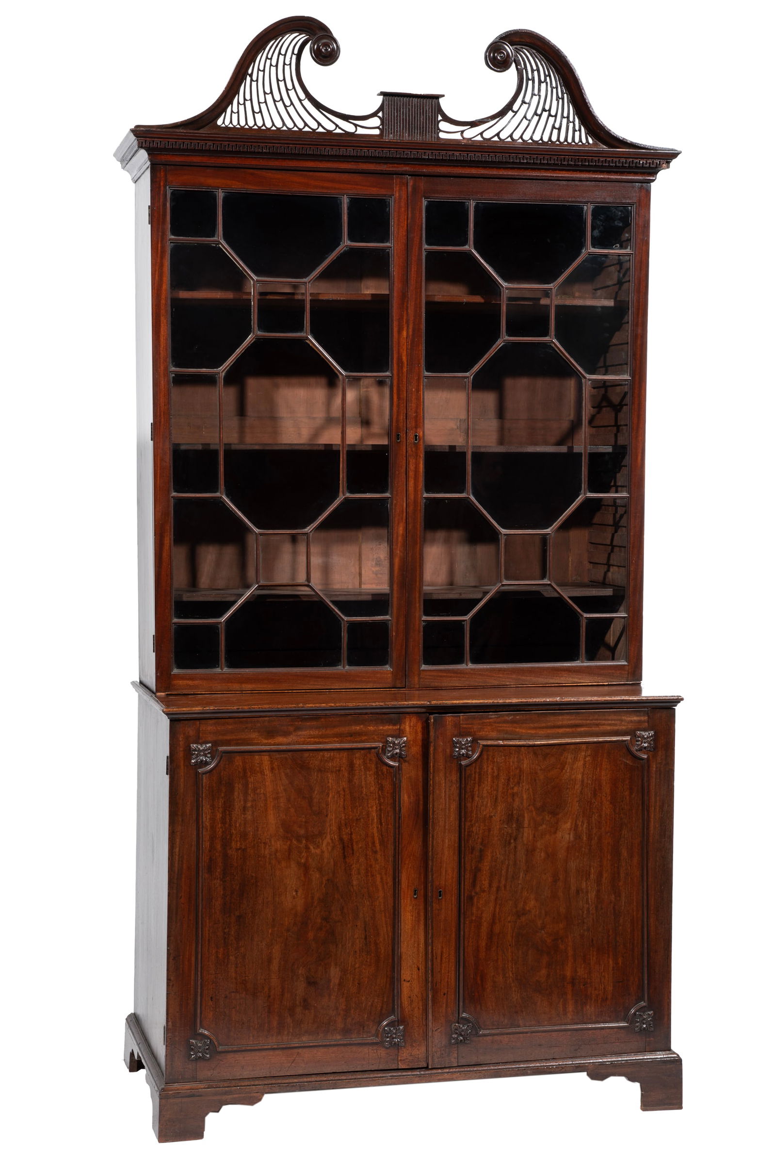 George III Carved Mahogany Bookcase: George III Carved Mahogany Bookcase 18th c., pierced broken arch pediment, molded cornice, glazed doors above molded paneled doors, fitted linen shelf interior, bracket feet 97 x 48 x 23 in. (246.4 x