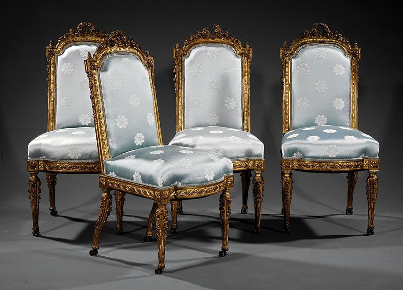 Six Louis XVI-Style Carved Giltlwood Salon Chairs: A Suite of Six Antique Louis XVI-Style Carved Giltwood Salon Chairs, comprising two fauteuils and four chaises, each with arched padded back surmounted by foliate wreath crest, molded arched seat rail