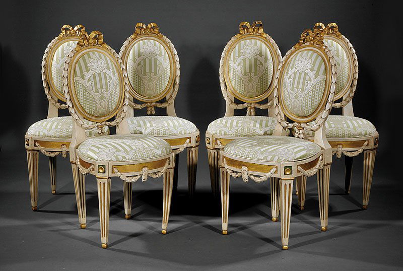 Six Carved Gilt, Crème Peinte Chaises: A Set of Six Neoclassical-Style Carved Gilt and Creme Peinte Chaises, each with beribboned crest, bellflower swag surround, paneled seat rail with conforming swags, square tapered fluted legs