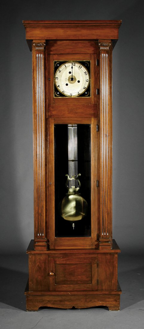 Carved Walnut "Rotating Dial" Tallcase Clock: An American Carved Walnut "Rotating Dial" Tallcase Clock, c. 1900, with electromechanical winder, the unusual movement with fixed hand painted on glass, the dial rotating to indicate time, height 90 i