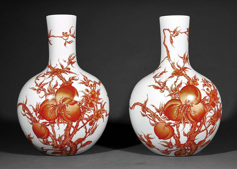 Chinese Iron Red Porcelain `Nine Peach' Vases: A Pair of Chinese Iron Red Porcelain `Nine Peach' Bottle Vases, probably 20th c., bulbous bodies with long necks decorated with nine peaches borne on flowering branches, bases with Qianlong marks, hei