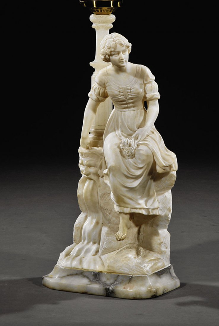 Carved Marble and Alabaster Figural Lamp: A Continental Carved Marble and Alabaster Figural Lamp, c. 1910, depicting a maiden on a rocaille base, carved with a grotesque mask issuing a waterfall, later glass shade, total height with shade 34