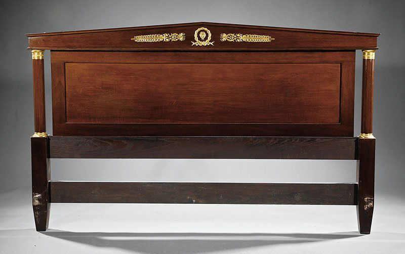 An Empire-Style Gilt Mahogany Bedroom Suite: An Empire-Style Gilt Bronze-Mounted Mahogany Bedroom Suite, c. 1950, benchmade, comprising a bedstead with arched crest, frieze centered by a masque within a wreath, paneled headboard flanked by colum