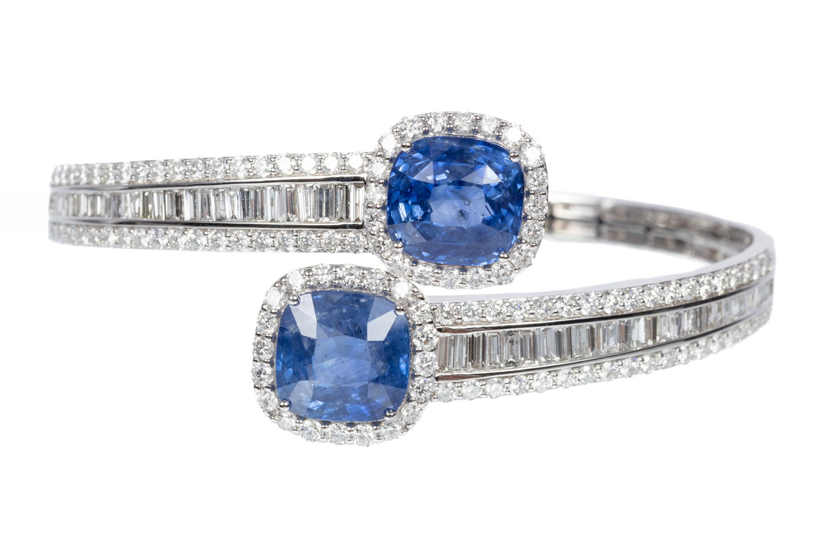 Platinum, Sapphire and Diamond Hinged Bangle Bracelet | 18.00 sapphire tcw: Platinum, Sapphire and Diamond Hinged Bangle Bracelet mounted with 2 cushion brilliant faceted cut sapphires, total wt. approx. 18.00 cts.; and 5.92 cts. of baguette and round brilliant cut diamonds;