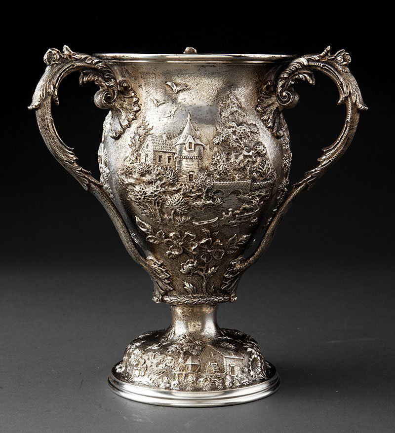 A Kirk Sterling Silver Repousse Tyg: A Kirk Sterling Silver Repousse Tyg, 1896-1924, marked "S KIRK & SON CO/925/1000"; footed vase form with foliate scroll handles, chased with landscape featuring village scenes with figures and various