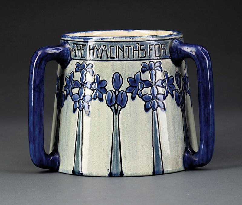 A Newcomb College Art Pottery High Glaze Tyg: A Newcomb College Art Pottery High Glaze Tyg, 1903, decorated by Mazie T. Ryan with hyacinth and the text "The Hyacinth's for Constancy with its Unchanging Blue", incised and glazed with dark blue, ba