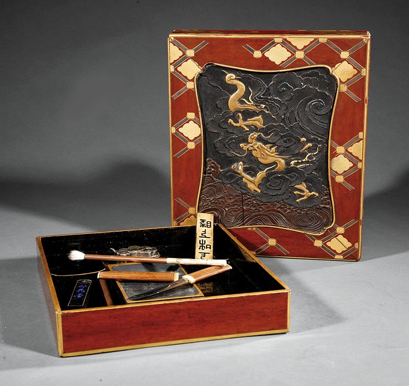A Japanese Inset Red Lacquer Writing Box, Suzuri: A Japanese Inset Red Lacquer Writing Box, Suzuribako, rectangular top with dragon carved inset panel, interior with inkstone, water dropper, ink sticks, brush, and knife, height 2 in., width 8 3/4 in.
