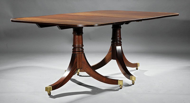 An Regency-Style Carved Mahogany Two Pede: An Antique Regency-Style Carved Mahogany Two Pedestal Dining Table, banded top, turned standards, saber legs, cuff casters, with two leaves, each 23 1/2 in, height 29 1/2 in., extended length 117 1/2