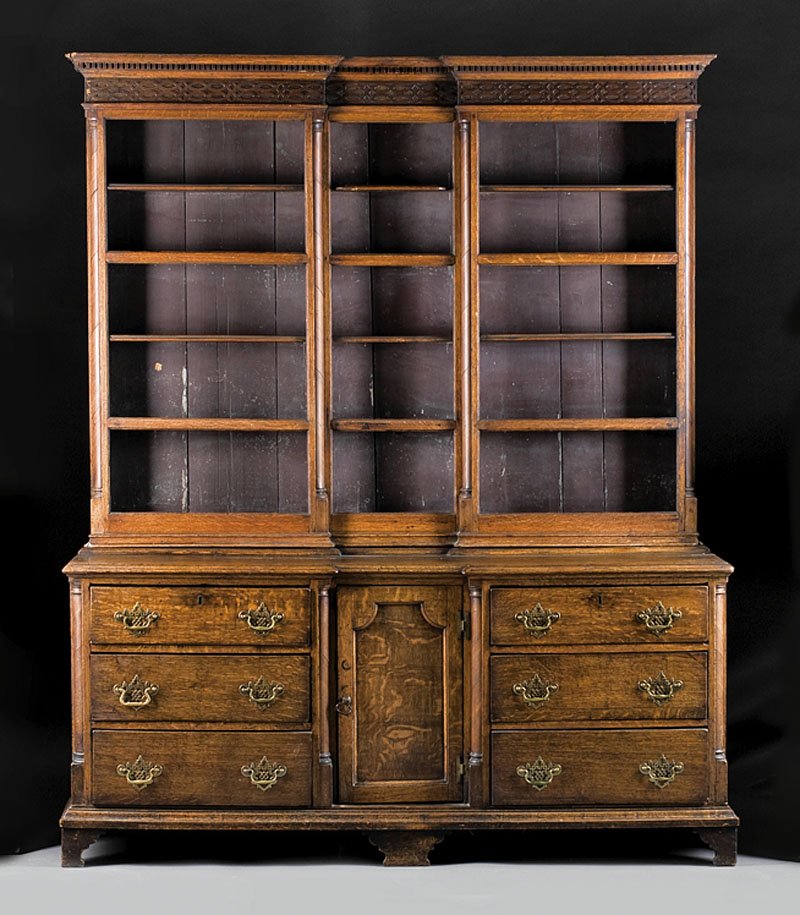 An English Carved Oak Welsh Dresser: An English Carved Oak Welsh Dresser, c. 1840, in two parts, upper plate rack with dentillated cornice and blind fretwork frieze, breakfronted base with banks of drawers flanking a center door amid col
