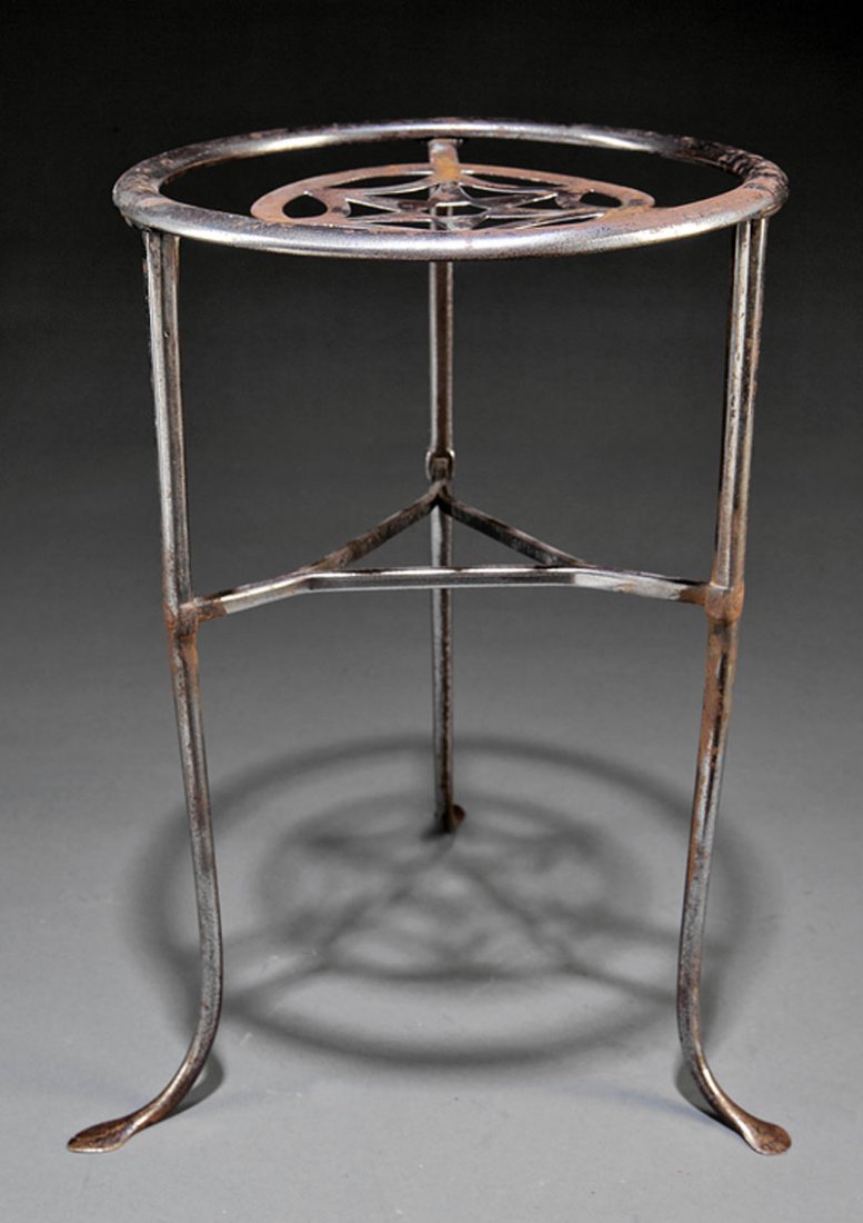 An American or English Steel Trivet: An American or English Steel Trivet, 19th c., three legs joined by stretcher, with reticulated star top, height 13 1/2 in., diameter 8 3/4 in.