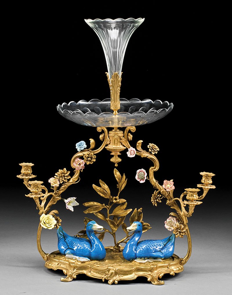 Porcelain-Mounted, Gilt Bronze, Cut-Glass Epergne: A Louis XV-Style Porcelain-Mounted, Gilt Bronze and Cut-Glass Epergne, late 19th c., trumpet vase rising from scalloped bowl, vine-form supports issuing candle branches applied with flowers, plateau w