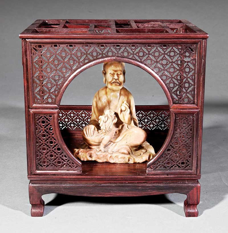 Chinese Soapstone Figure of Laughing Lion Luohan: A Good Chinese Soapstone Figure of the Laughing Lion Luohan, Vajraputra, probably 18th c., carved seated in monk's robes playing with a lion cub, height 5 1/8 in., presented in wood model of a bed, ov