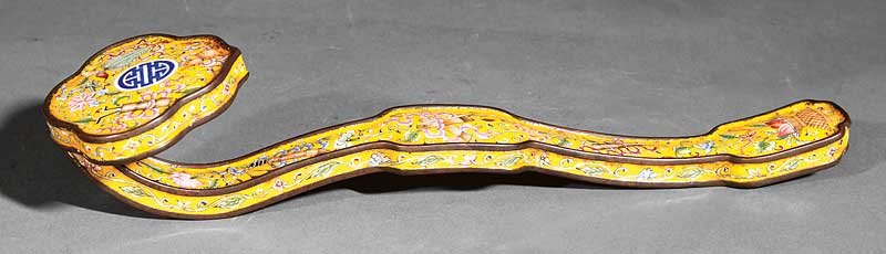 A Chinese Canton Enamel Ruyi Scepter: A Chinese Canton Enamel Ruyi Scepter, probably Qing Dynasty (1644-1911), undulating shaft ending in a ruyi head terminal decorated with antiques, flowers and a shou character on a yellow ground, lengt