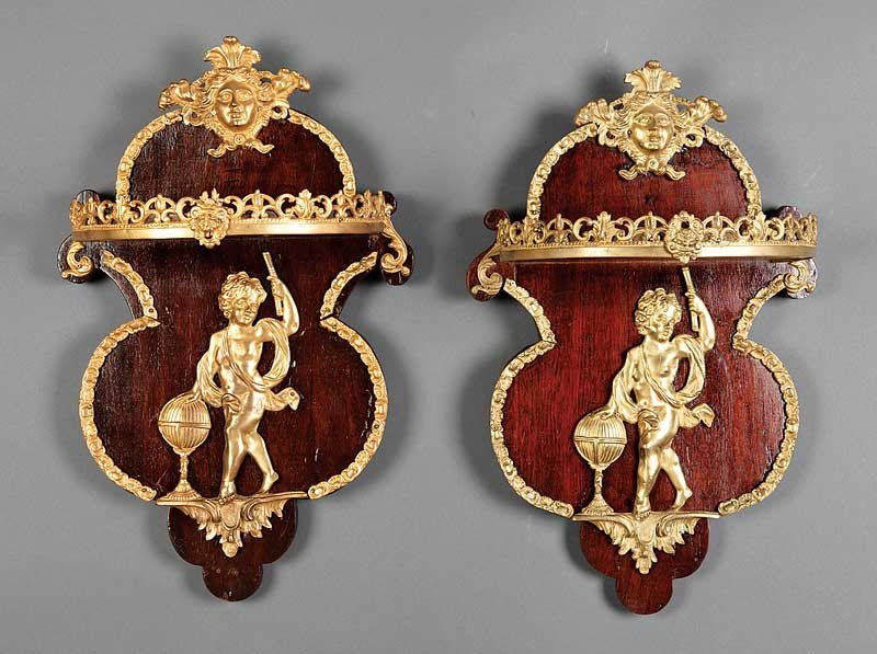Gilt Bronze-Mounted Mahogany Wall Brackets: A Pair of Louis XVI-Style Gilt Bronze-Mounted Mahogany Wall Brackets, each with mask crest, shelf with reticulated scrolled gallery, shaped back with allegorical putto, height 24 in., width 13 in., de