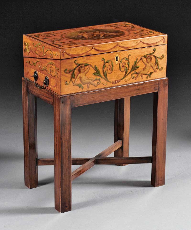 An Edwardian Paint-Decorated Satinwood Lap Desk: An Edwardian Paint-Decorated Satinwood Lap Desk, 19th c., in the Adam taste, hinged lid centering reserve of putti, fitted interior with baize writing surface, one side fitted with a long drawer, carr