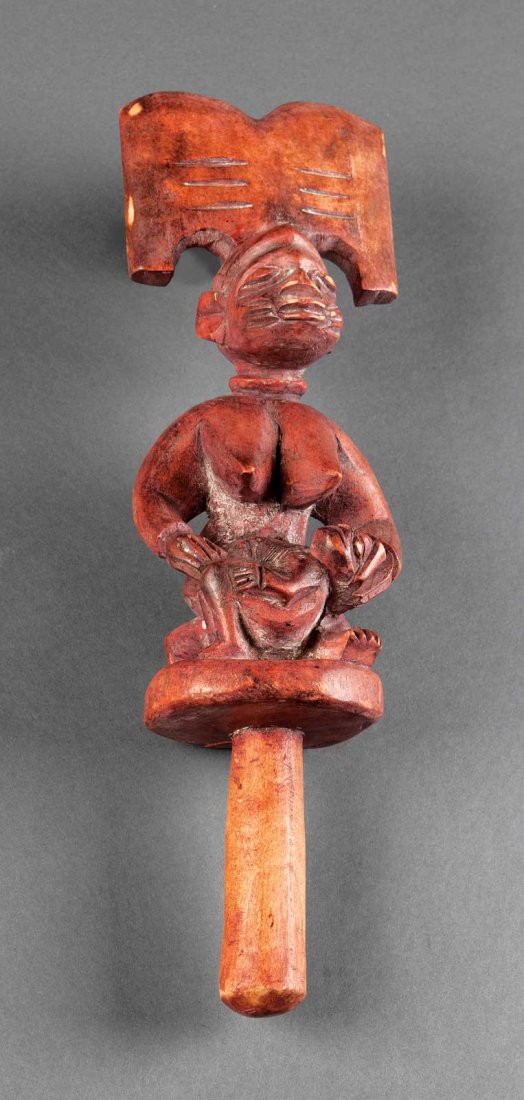 A Yoruba Carved Wood Dance Staff: A Yoruba Carved Wood Dance Staff, Nigeria, cylindrical shaft surmounted by a seated female nude cradling a child, height 15 1/4 in . Provenance: Property of the High Museum of Art, Atlanta, GA (no. SC