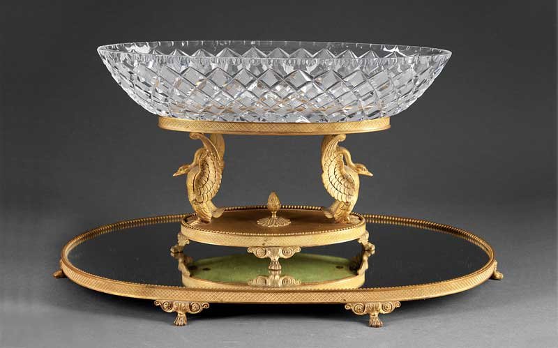 Gilt Bronze and Cut Crystal Centerpiece: A Charles X-Style Gilt Bronze and Cut Crystal Centerpiece, c. 1900, oval bowl supported by swans, beaded and diapered decoration, on conforming mirrored plateau, paw feet, height 12 1/2 in., width 23 