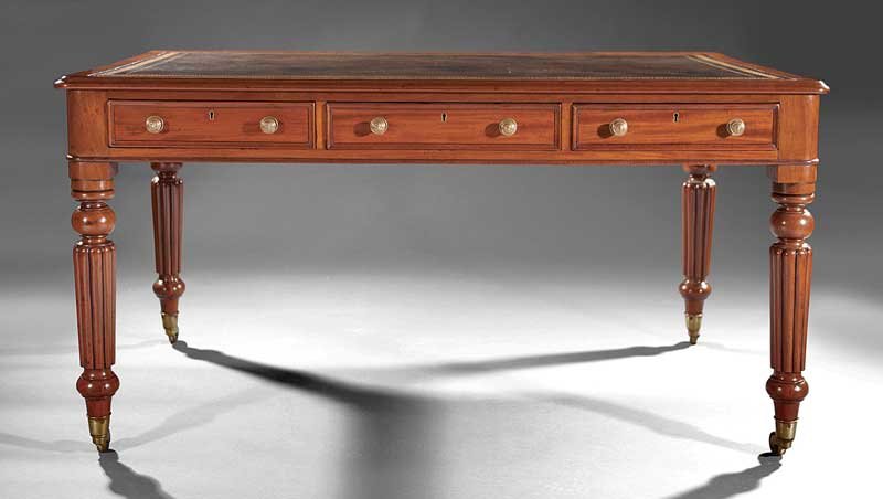 A William IV Mahogany Writing Table: A William IV Mahogany Writing Table, early 19th c., inset Greek key tooled leather writing surface, three drawers on each side, turned, reeded tapered legs ending in brass cuffs, casters, height 30 1/