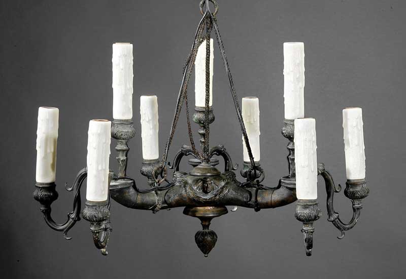 Patinated Bronze Nine-Light Chandelier: A Continental Patinated Bronze Nine-Light Chandelier, 19th c., modeled as a triple nozzled ancient oil lamp with Bacchic masks and swags, each spout issuing three candlearms, height 26 in., width 18 i