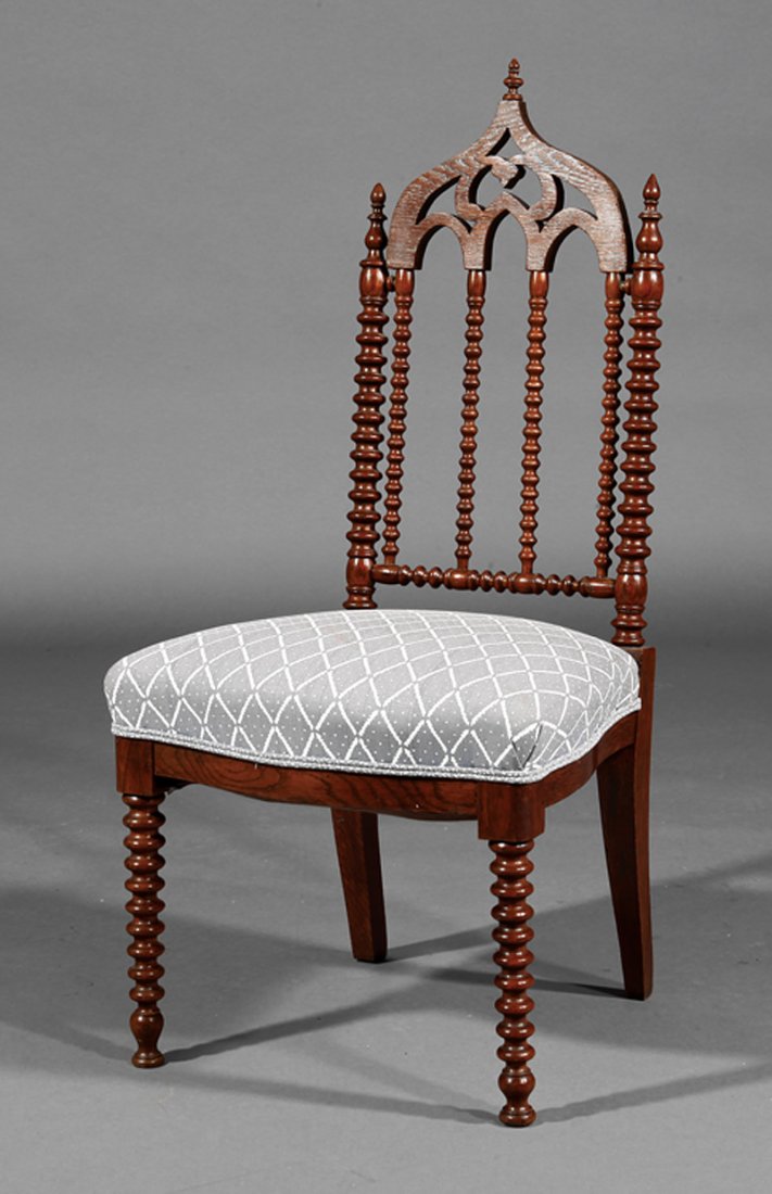 An American Gothic Carved Mahogany Hall Chair: An American Gothic Carved Mahogany Hall Chair, late 19th c., arched tracery back, spool-turned uprights and legs. Note: Lacks casters