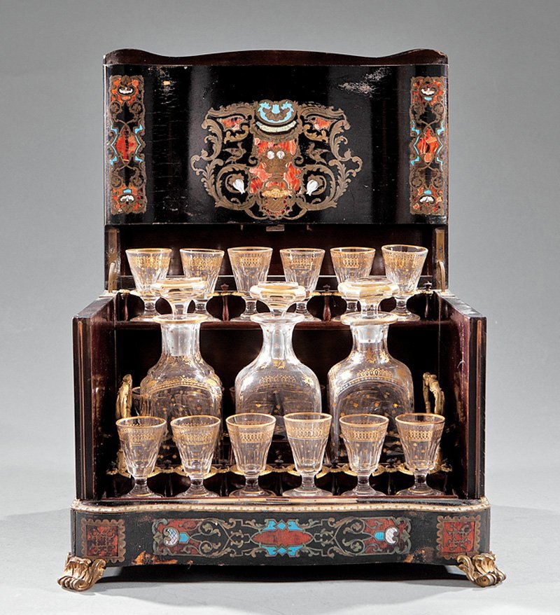 Enameled, Mother-of-Pearl Inlaid Cave à Liqueur: A Napoleon III ebonized, Enameled and Mother-of-Pearl Inlaid Cave à Liqueur, hinged serpentine top with central crest bearing the monogram "MW" beneath a coronet, opening to reveal a fitted interior