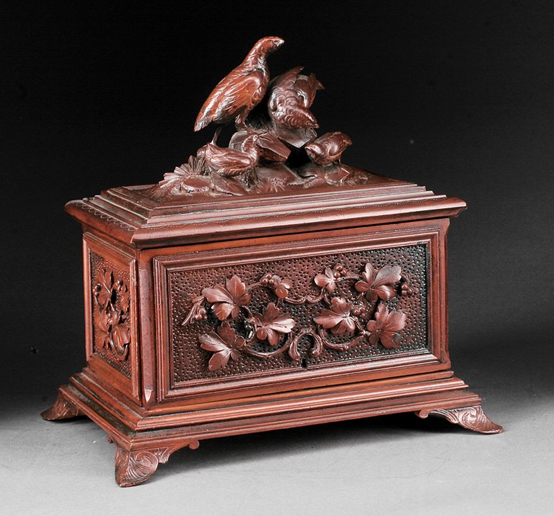 A Continental Black Forest Carved Walnut Humidor: A Continental Black Forest Carved Walnut Humidor, c. 1900, hinged top surmounted by pheasants, floral carving on stippled ground, interior with fitted cigar trays, height 12 1/2 in., width 13 in., dep