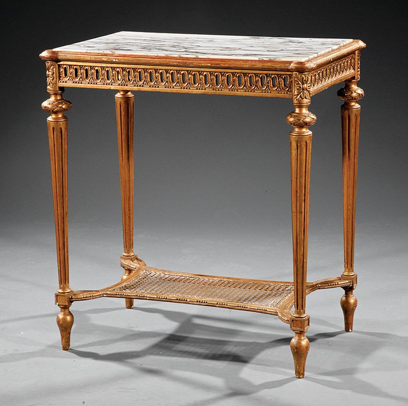 A Louis XVI-Style Carved Giltwood Center Table: A Louis XVI-Style Carved Giltwood Center Table, early 20th c., inset marble top, outset corners, conforming reticulated frieze, tapering fluted legs, caned stretcher shelf, height 30 in., width 27 1/2