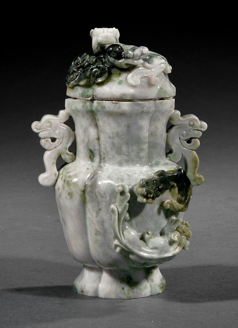 A Chinese Jadeite Covered Vase: A Chinese Jadeite Covered Vase, 20th c., mottled pale and dark green and white stone carved in lobed bottle-form with zoomorphic handles and a pair of confronting Buddhist lions, conforming domed cove