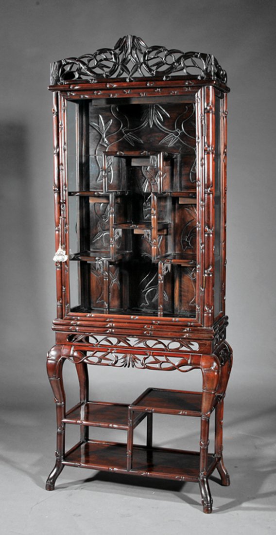 A Chinese Carved Hardwood Vitrine: A Chinese Carved Hardwood Vitrine, probably early 20th c., pierced "bamboo" crest over glass upper case fitted with tiered shelves set on open shelf base with pierced bamboo apron on tall cabriole leg