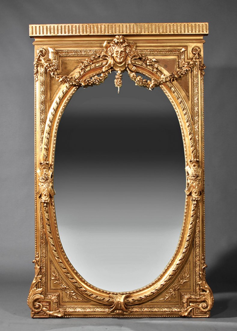 A French Neoclassical-Style Gilt Mirror: A Monumental French Neoclassical-Style Gilt Mirror, fluted cornice, oval mirror plate within a molded surround with masque crest and foliate garlands, height 89 1/4 in., width 56 1/2 in