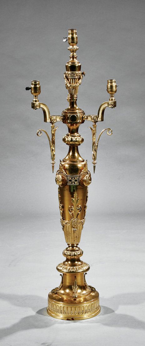 Gilt Brass Four-Light Newel Post Fixture: An American Renaissance Gilt Brass Four-Light Newel Post Fixture, late 19th c., tapered vasiform body mounted with cupid masks and anthemia, bracketed light sockets, circular base, height 45 in., diam