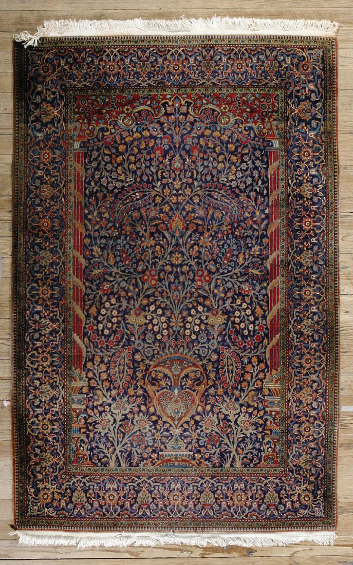 An Persian Carpet: An Antique Persian Carpet, navy blue ground, central field, urn issuing floral motif surrounded by a mihrab, polychrome floral border, 6 ft. 9 in. x 4 ft. 5 in